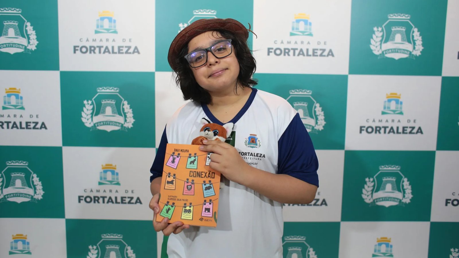 Davi Moura posa para a foto segurando seu livro